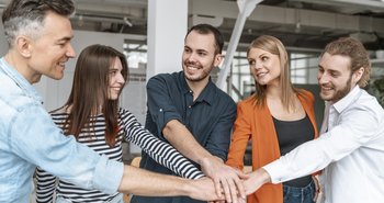 Geschäftsleute im Büro halten Hände zusammen