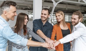 Geschäftsleute im Büro halten Hände zusammen